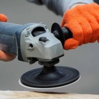 Worker grinds the wood of angular grinding machine